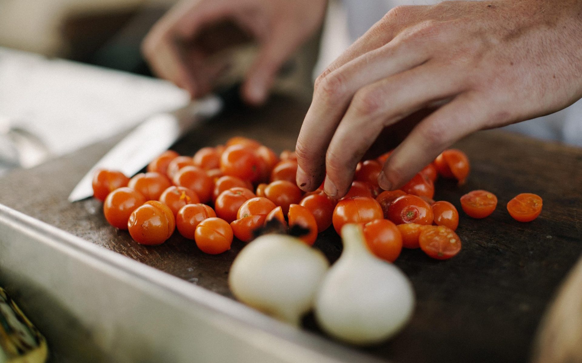 Koch schneidet Zwiebel und Tomaten für eine Sauce